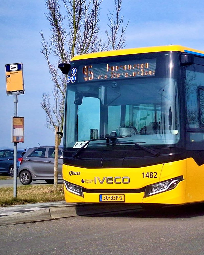 Lijn 95 staat stil bij een halte met een windmolen op de achtergrond