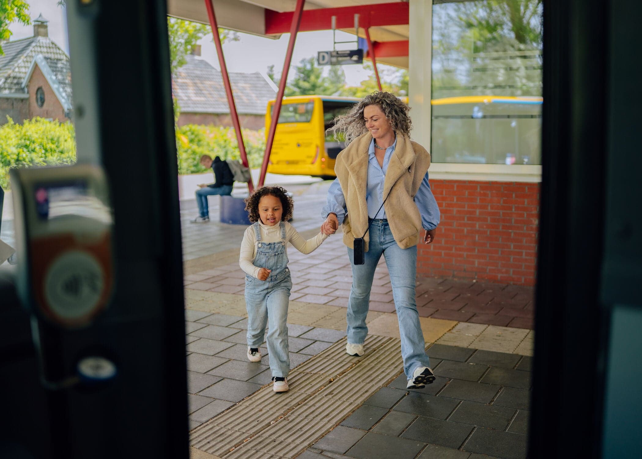 Moeder en kind komen bij de bus aanlopen
